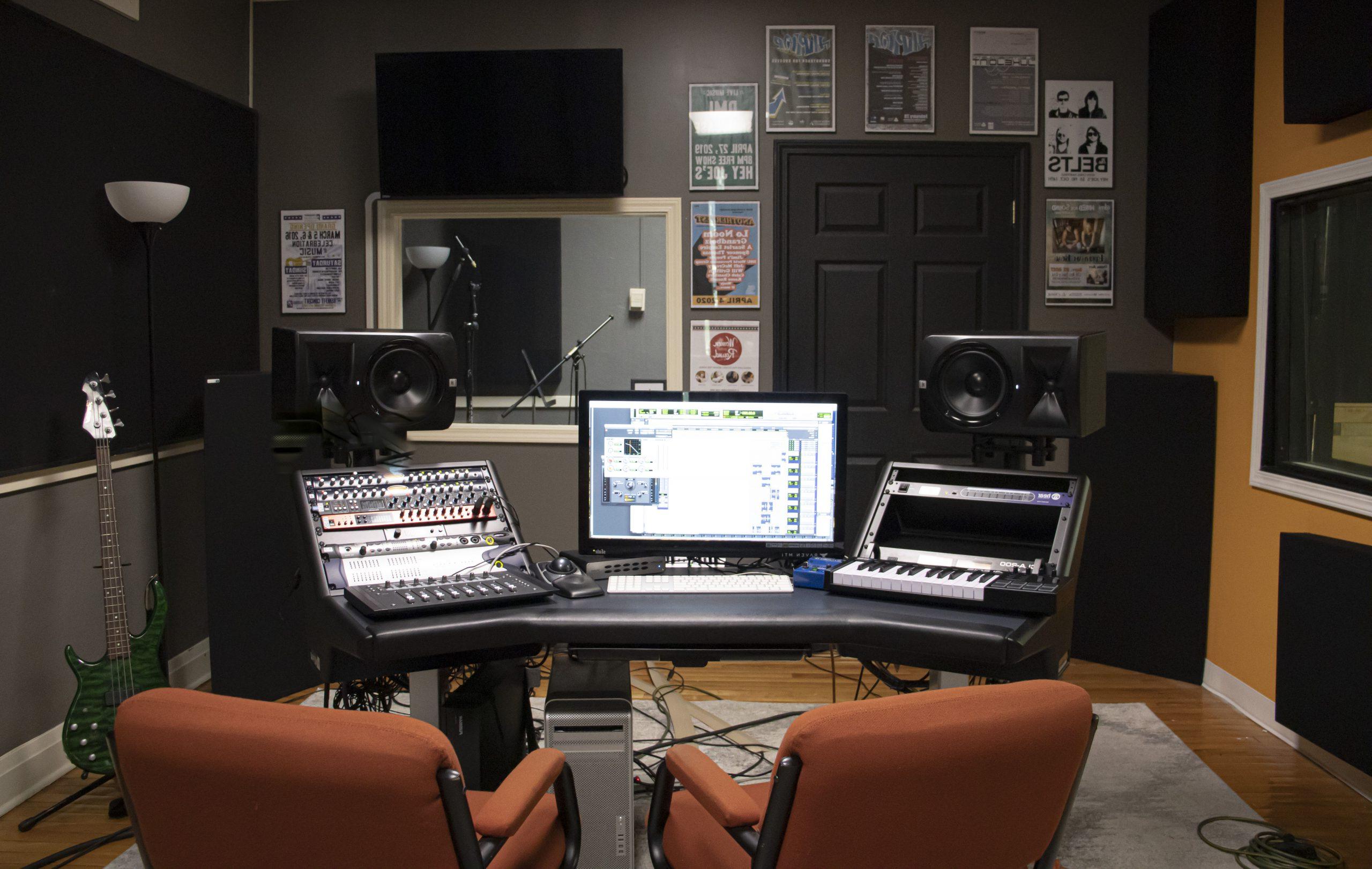 Small recording studio with recording equipment on each site of the computer screen.
