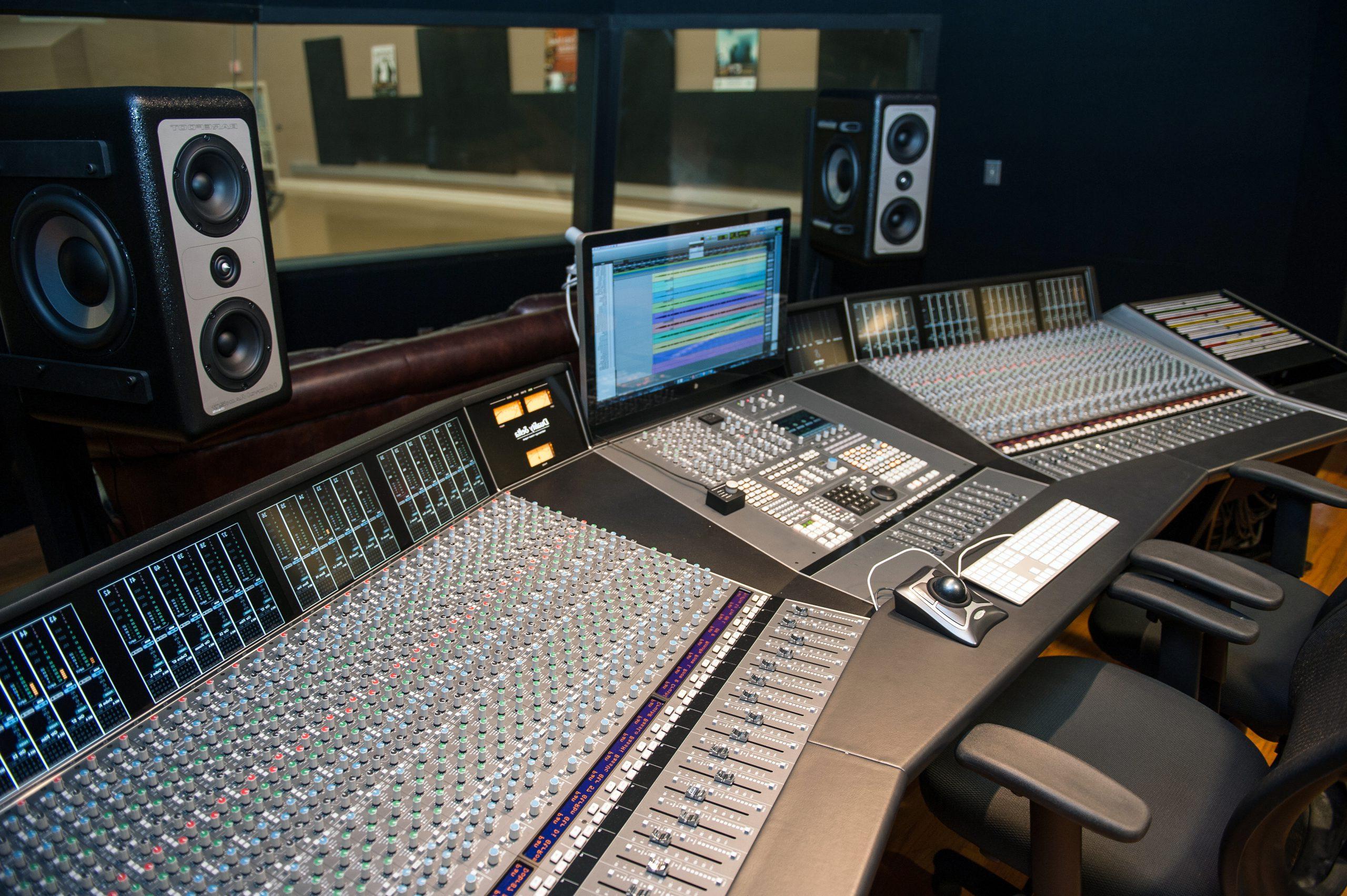 Large studio console powered on in the control room.